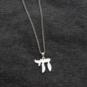 May include: A silver chain necklace with a silver pendant shaped like the Hebrew letter 'Chai'.