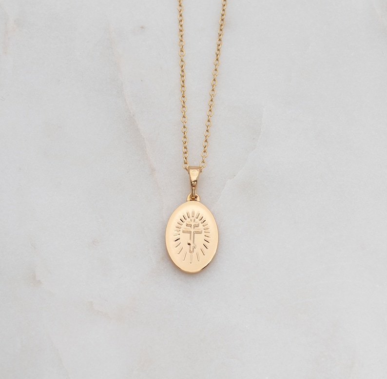 May include: A gold chain necklace with a pendant featuring a cross inside a circle.