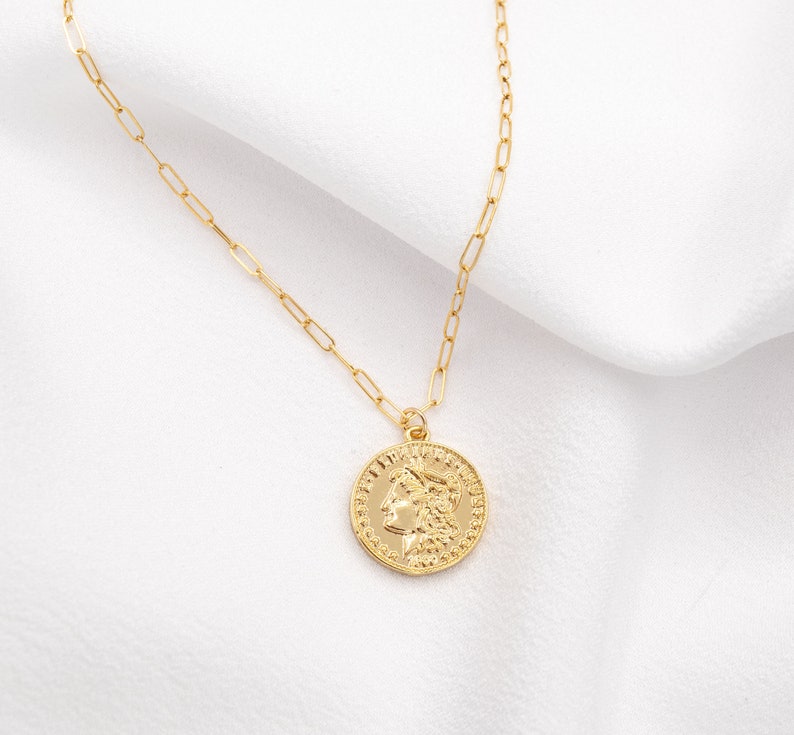 May include: A gold chain necklace with a gold coin pendant featuring a profile of a woman's face.