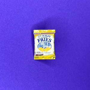 May include: A packet of Scampi Fries crisps, with a yellow and white design. The text 'Scampi Fries' is in blue, with a picture of the product. The packet is on a purple background.