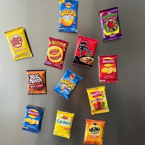 May include: A collection of 12 different snack food bags, including Wotsits, Monster Munch, Skips, Hula Hoops, Nik Naks, Quavers, Mini Cheddars, Jelly Babies, and Walkers. The bags are all different colours and have various designs.