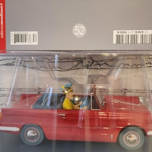 Peut inclure: Une voiture d&eacute;capotable rouge jouet avec deux personnages &agrave; l'int&eacute;rieur. La voiture porte la plaque d'immatriculation "OUK 586". Les personnages portent des chapeaux et ressemblent &agrave; des personnages de dessins anim&eacute;s. La voiture est dans un emballage en plastique transparent.