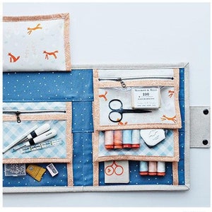 May include: A blue and white fabric folio with multiple pockets and compartments for sewing supplies. The folio is 10 inches by 12 inches and has a zippered closure. The folio is open and shows various sewing supplies, including scissors, thread, and needles.