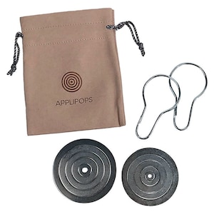 May include: Two silver metal shower rings, a brown velvet drawstring bag with the logo "APPLIPOPS" and a red circle design, and two silver metal discs with concentric circles.