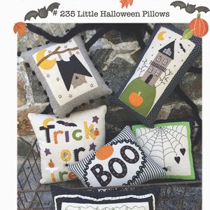 May include: Five Halloween-themed pillow covers with various designs, including a bat, a house, a spiderweb, a pumpkin, and the words "Trick or Treat" and "Boo". The pillow covers are arranged in a metal basket on a stone background. The text "#235 Little Halloween Pillows" is visible at the top of the image.