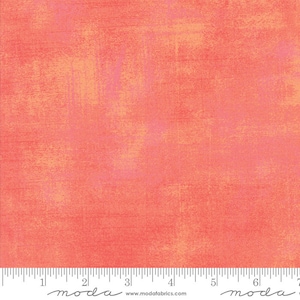 May include: A close-up of a coral-colored fabric with a subtle textured pattern. The fabric has a slightly distressed look, with a hint of pink and orange throughout. The fabric is measured in inches with a ruler at the bottom of the image. The ruler has the word "moda" printed on it.