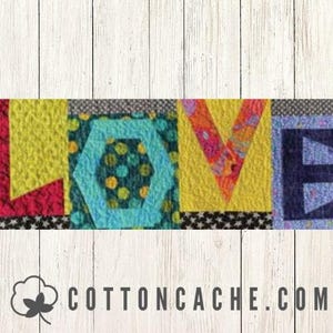 May include: A colorful textile art piece spelling out the word "LOVE". Each letter is a different color and pattern, including yellow, red, blue, and a turquoise hexagon. The background is a light wood grain.
