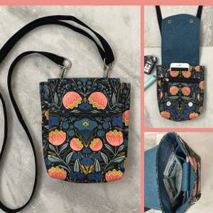 May include: A black and white floral print crossbody bag with a zipper closure and a clip on the front. The bag is 7 inches high, 6 1/2 inches wide, and 2 inches deep. The bag is shown with a black strap and a blue denim lining.