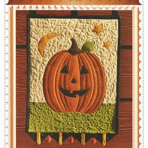 May include: A quilted wall hanging featuring a smiling orange pumpkin with a green stem and leaf, a crescent moon, and stars. The words "Mr. Jack" and "Wall Hanging" are at the bottom. The background is a cream color with a wood-grain pattern.