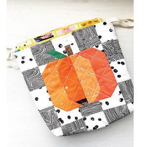 May include: A black and white fabric drawstring bag with a quilted orange pumpkin design. The bag measures 8 inches by 10 inches by 2 inches. "Mini Pumpkin Drawstring Bag Project" is written at the top of the image.
