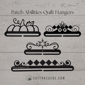 May include: Black metal quilt hangers in various decorative designs, including a pumpkin, a snowflake, and geometric patterns. The text "Patch Abilities Quilt Hangers" is at the top. The website "cottoncache.com" is at the bottom.