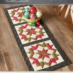 May include: A Christmas star runner table runner with a red, green, and white star pattern. The runner is 15.5 inches by 42.5 inches.