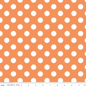 May include: Orange fabric with a repeating pattern of large white polka dots. The fabric has a ruler along the bottom edge with inch measurements. The text "Riley Blake Designs" is visible.