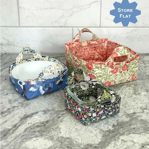 May include: Three patterned microwave baskets in different sizes. The baskets have handles and are designed to flip up for use and fold flat for storage. The text on the image says "Flip and Heat Microwave Baskets".