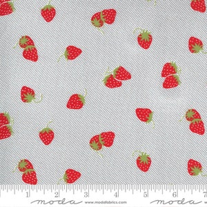 May include: A white fabric with a repeating pattern of red strawberries. The fabric has a subtle grid pattern. The fabric is measured with a ruler in inches.