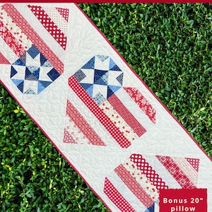 May include: A red, white, and blue patriotic table runner with a star-spangled design. The table runner is 23 inches wide and 67 inches long. The image also includes a bonus pillow pattern that is 20 inches wide.