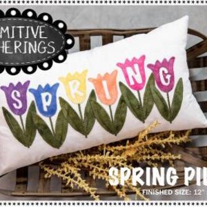 May include: A white pillow with the word "SPRING" spelled out in colorful tulips. The pillow is sitting in a wooden basket and has a "Primitive Gatherings" label in the top left corner. The pillow is 12 inches by 22 inches.