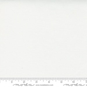 May include: A white fabric with a subtle texture. The fabric is measured with a ruler that has the word "moda" printed on it.