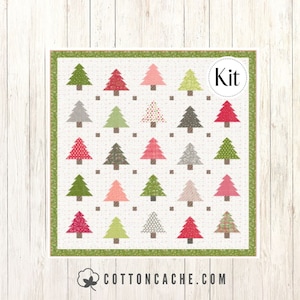 May include: A quilt kit featuring a pattern of colorful Christmas trees on a white background. The kit includes all the fabric needed to make a quilt. The text "Kit" is displayed in a circle on the image.