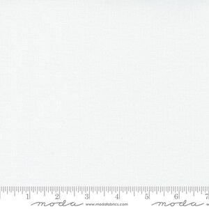 May include: A plain white fabric with a subtle texture. The fabric is measured with a ruler that has the word "moda" printed on it.