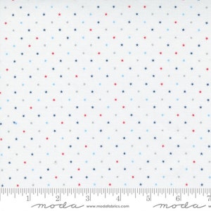 May include: White fabric with a repeating pattern of small stars in red, blue, and gray. The stars are evenly spaced across the surface. A ruler is printed along the bottom edge.