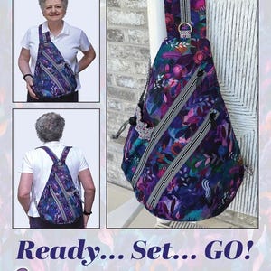 May include: The AeroSling is a teardrop-shaped crossbody bag featuring a dark floral pattern in shades of purple, blue, and pink. It includes multiple zippered compartments, a cord-locked water bottle pouch, and measures 14.5 inches high by 11 inches wide by 5 inches deep.