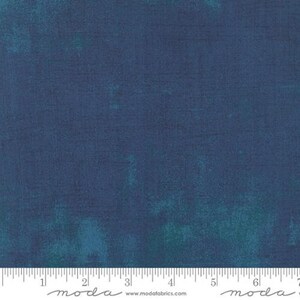 May include: A solid blue fabric with a subtle mottled texture. The fabric is a medium blue with a hint of green in the mottled areas. The fabric is shown with a ruler for scale.