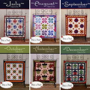 May include: Six quilt patterns for each month of the year, July through December. Each pattern is displayed on a black metal stand with a white background. The patterns are all different and feature various colors and designs.