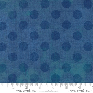May include: Blue fabric with a repeating pattern of large, dark blue circles. The fabric has a textured appearance with subtle variations in color, ranging from deep blue to teal. The word "moda" is printed at the bottom of the fabric.