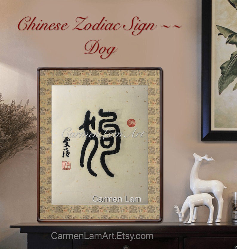 Puede incluir: Una obra de arte de caligraf&iacute;a enmarcada que presenta el car&aacute;cter chino para "perro" en tinta negra sobre un fondo beige. La obra de arte se titula "Signo del zod&iacute;aco chino - Perro" y est&aacute; firmada por "Carmen Lam".