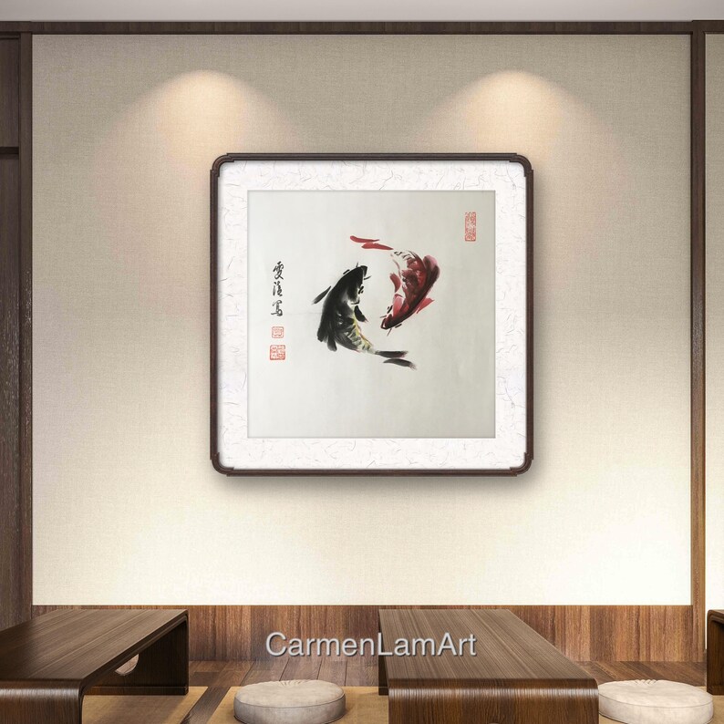 May include: Framed artwork featuring two koi fish in a traditional Asian ink painting style. One fish is black, the other red, swimming in opposite directions. The artwork is displayed on a neutral-toned wall.