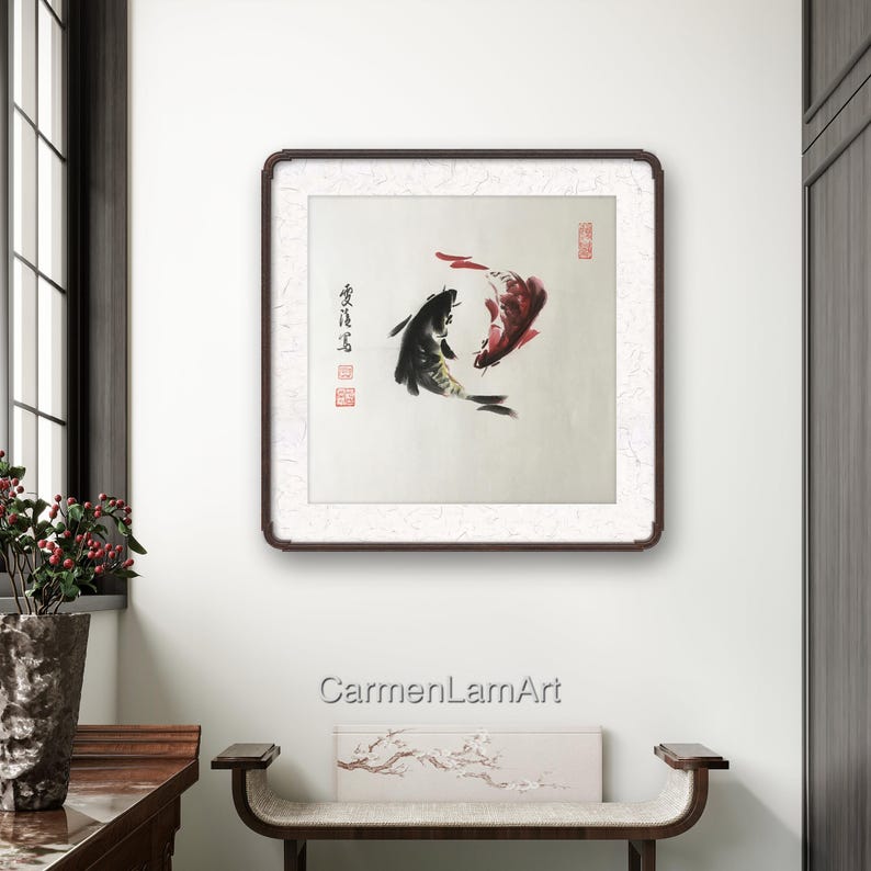 May include: Framed artwork featuring two koi fish in a traditional Asian style. One fish is black, the other red, swimming in opposite directions. The artwork includes Chinese characters and is set against a textured background.