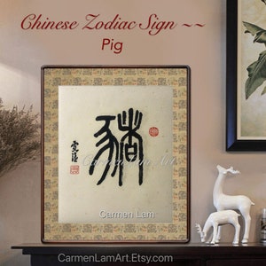 Puede incluir: Una obra de arte de caligraf&iacute;a enmarcada del signo del zod&iacute;aco chino para el Cerdo, escrita en tinta negra sobre un fondo beige. La obra de arte se titula "Cerdo" y est&aacute; firmada por "Carmen Lam".