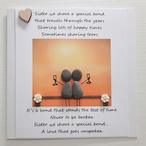 May include: A card featuring a hand-painted pebble art design of two figures holding glasses of champagne. The card has a poem about sisterhood that reads "Sister we share a special bond that travels through the years Sharing lots of happy times Sometimes sharing tears It's a bond that stands the test of time Never to be broken Sister we share a special bond... A love that goes unspoken"