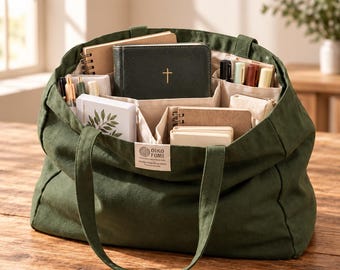 Może przedstawiać: Ciemnozielona torba typu tote z płótna z dwoma uchwytami i metką OIKO FOMI z przodu. Wnętrze posiada liczne przegródki z beżowego materiału wypełnione różnymi notatnikami, ciemnozieloną książką ze złotym krzyżem oraz kilkoma długopisami.