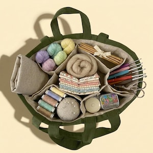 May include: A dark olive green fabric tote bag with multiple interior compartments filled with craft supplies, including yarn balls, wooden knitting needles, crochet hooks, fabric squares, sewing thread spools, a pin cushion, and scissors.