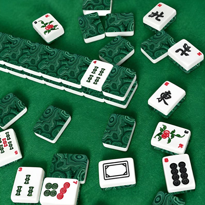 May include: A set of mahjong tiles featuring a deep green malachite-style marbled pattern on the backs. The front faces are white with black, red, and green engraved characters, numbers, and floral motifs, arranged in a scattered layout.