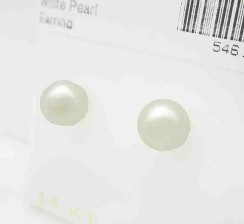 Op de afbeelding: Twee witte parel oorbellen op een witte achtergrond. De oorbellen zijn rond en hebben een glad oppervlak.