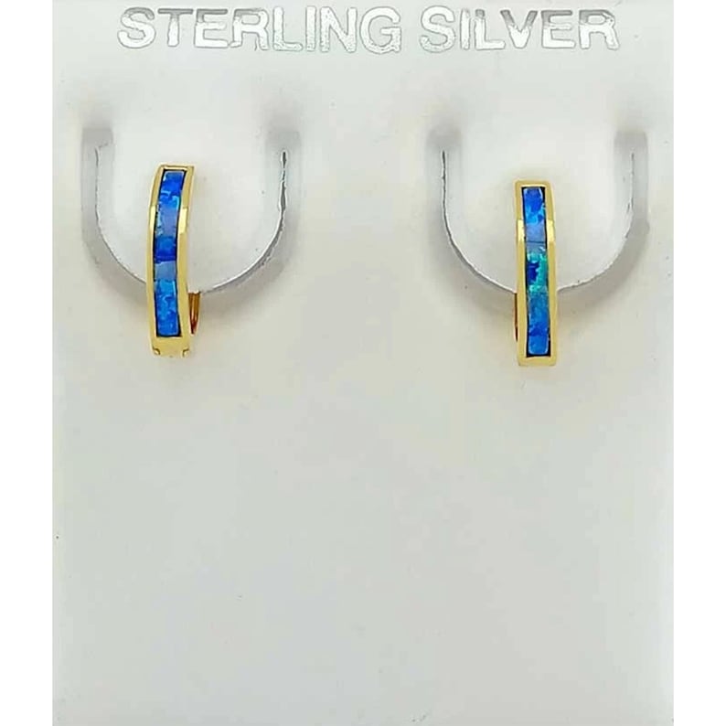 May include: Gold-coloured hoop earrings, each with a rectangular inlay of blue and teal stones. The earrings are displayed on a white background with the text "STERLING SILVER" at the top.