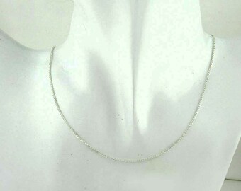 May include: A silver chain necklace on a white mannequin.