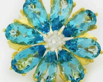 May include: A gold flower brooch with blue topaz stones and a small diamond in the center.