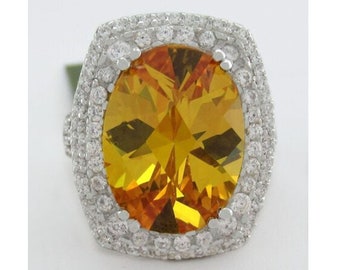 May include: A silver ring with a large oval-shaped topaz gemstone surrounded by a double row of smaller clear gemstones.