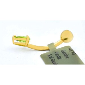 May include: A gold 14k yellow gold body piercing with a green peridot gemstone. The tag reads "Genuine Peridot & W Sand 14k YG".