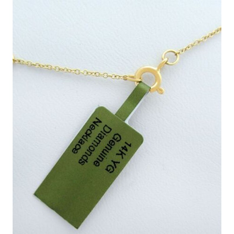 Pode incluir: Um colar de corrente de ouro com um fecho, do qual pende uma etiqueta verde com o texto "14K YG Genuine Diamonds Necklace".