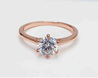 May include: A rose gold engagement ring with a round, clear center stone.