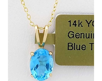 Puede incluir: Un collar dorado con un colgante con una gema azul claro de forma ovalada. La cadena es delicada. La etiqueta dice "14k Y Genuine Blue T".