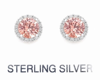 May include: Two sterling silver stud earrings with a large, round, peach-colored center stone surrounded by a halo of smaller, clear stones. The text "STERLING SILVER" is printed below the earrings.