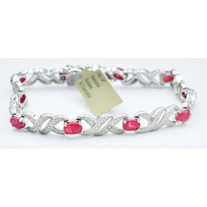 May include: A silver bracelet with oval-cut red gemstones and small white diamonds. The bracelet has an X and O design. A tag reads "14K GP Genuine Rubies & Diamond".
