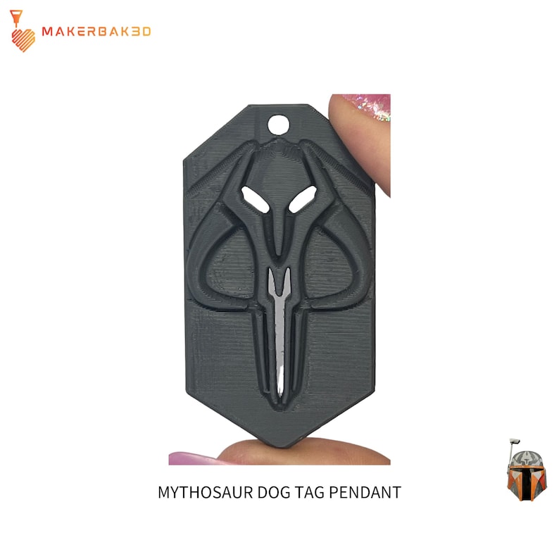 May include: A dark gray Mythosaur dog tag pendant. The pendant features a detailed design of the Mythosaur skull symbol with a hole at the top for attachment. The text "MYTHOSAUR DOG TAG PENDANT" is at the bottom.