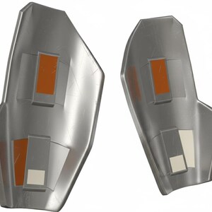Pu&ograve; includere: Due protezioni per le braccia argentate metalliche con accenti rettangolari arancioni e bianchi. Le protezioni per le braccia hanno una forma leggermente curva e sembrano essere realizzate in un materiale resistente. Il design suggerisce un tema futuristico o fantascientifico.